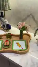 A beautifully styled home decor vignette is showcased in this video. The camera pans across a marble countertop, revealing a charming ceramic dog lamp, a woven tray with decorative placemats and snacks, and a vase of fresh flowers. The overall aesthetic is cozy and inviting, perfect for a relaxing morning or afternoon tea. by @moneeragh with Original Sound by moneeragh