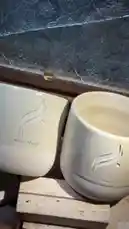 A close-up showcase of two pristine white ceramic bowls featuring elegant Arabic calligraphy designs. The bowls are displayed within a wooden presentation box with a decorative glass top, highlighting their craftsmanship and aesthetic appeal. This video captures the intricate details and minimalist elegance of these handcrafted pieces. by @r200an with original sound
