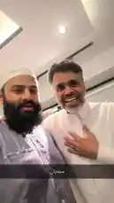 In a brightly lit indoor setting, a man wearing a white thobe and another man in a grey thobe and white kufi engage in a warm and friendly interaction. They shake hands, smile, and converse, creating a moment of camaraderie and respect. The atmosphere is positive and celebratory. by @om-5p with Original Sound by om-5p
