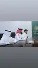 A formal gathering at Al-Rawdah Club in Saudi Arabia features key figures in traditional attire, including a man in a white thobe and ghutra alongside others in business wear. The meeting takes place around a polished conference table under professional lighting, with branding for 'نادي الروضة السعودي' visible on a backdrop, suggesting discussions on club affairs or organizational development. by @alrawdahclub with original sound