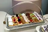 A beautifully arranged dessert platter filled with an assortment of pastries, cakes, tarts, and fruit-topped confections. The elegant glass tray with a silver handle presents a variety of sweet treats, including cream-filled éclairs, chocolate-dipped delights, and berry-topped petit fours. This visually appealing display highlights gourmet dessert presentation perfect for events, parties, or culinary showcases. by @blue11sweet with original sound