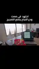 A behind-the-scenes look at a modern office environment from 'Modern Solutions'. The desk features a laptop displaying a presentation slide about 'النجاح يصنع الضجيج' ('Success Creates Noise'), alongside a prominent red KitKat chocolate bar package. Two small flags stand on the desk near a large window overlooking a cityscape. by @modernsolutionn with Original Sound by modernsolutionn