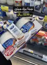 A close-up shot of a hand holding a Puck Original yogurt pack on a supermarket shelf. The packaging features a 'Special Offer' label and a QR code. Arabic text overlays highlight the price as '22.99 ريال' and promote the product as 'جبنه بوك حبتين' (Two Puck Cheese). The background shows other dairy products, suggesting a refrigerated grocery section. This scene captures a real-time shopping moment focused on a budget-friendly deal. by @hyperalwafa with original sound