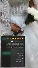 A stunning close-up shot focuses on the hands of a bride, showcasing intricate henna designs and a beautiful ring. She holds a bouquet of white roses, all set against the delicate lace of her wedding dress. This elegant moment captures the artistry and detail of bridal preparations. by @rii.38 with فين التحيه بتاعت الملكه؟ by .