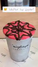 A close-up shot of a vibrant red drink from Sequence Coffee, topped with an intricate chocolate drizzle pattern. The cup features the brand's logo, and Arabic text is overlaid on the screen, creating a visually appealing and trendy beverage presentation. by @sequence-coffee with 🧘‍♂️💌🍻🪕🦙 by 🦋