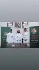 في لحظة رسمية، يُظهر هذا المشهد توقيع اتفاقية تعاون بين نادي الروضة السعودي والمؤسسة الاجتماعية. يقف ثلاثة رجال بملابس تقليدية سعودية أمام طاولة، ويتم تسليم وثائق رسمية، مما يعكس التزامًا بالشراكة المجتمعية. الخلفية تحتوي على شعارات الناديين، مما يعزز أهمية هذه المناسبة الرسمية. by @alrawdahclub with original sound