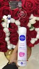 A hand holds up a can of Nivea Fresh Flower deodorant spray against a beautiful backdrop of red and white roses. The product is clearly visible, showcasing its '0% Aluminum Salts' feature. The DS Drogerie Store logo and contact information are displayed on screen, promoting their German-based delivery service. by @dsdrogeriestore with DS🇩🇪 by DS drogerie store🇩🇪