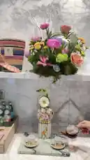 A serene moment featuring a hand gracefully pouring tea into delicate cups. The scene is beautifully set against a marble backdrop, adorned with vibrant floral arrangements and a charming woven basket. This tranquil setup captures the essence of a sophisticated tea experience. by @moneeragh with Original Sound by moneeragh