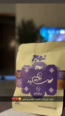 A close-up showcase of Nahj Roastery's beautifully designed coffee packaging, highlighting its elegant purple and cream branding, Arabic calligraphy, and product details like '20g' weight and 'براليي' label. The stylish presentation emphasizes quality and cultural identity. by @ru.ab71 with original sound