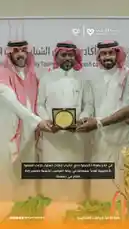 This video captures a formal award ceremony hosted by the Saudi Players' Association. Three men in traditional Saudi attire stand together as one presents a golden commemorative plaque to another. The event celebrates youth football achievements, with Arabic text overlay confirming the honor for 'outstanding youth players.' The atmosphere is celebratory and official, highlighting the importance of youth development in Saudi sports. by @playerassoc with original sound
