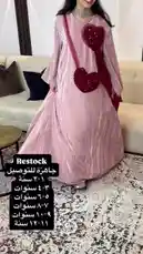 A model showcases a stunning pink pleated abaya from Artal Fashion's latest restock. The elegant gown features long sleeves and is accessorized with a matching red heart-shaped embellished bag. On-screen text details the available sizes for this new arrival. by @artal.street with original sound