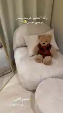 Watch as interior designer Aaththy showcases a beautifully styled corner of her living room. The scene features a plush beige armchair with a matching ottoman, accented by a charming teddy bear wearing a red plaid shirt. The soft textures and neutral tones create a warm and inviting atmosphere, perfect for relaxation. This simple yet elegant setup demonstrates how to achieve a cozy aesthetic with minimal decor. by @aththy1 with Original Sound by aththy1
