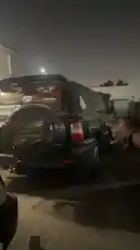 In this nighttime scene, a custom black SUV, likely owned by Ammar Sheikh, is the center of attention. The vehicle features a spare tire cover with 'Landrover' branding and a red graphic decal on the rear window. A person is seen filming the SUV with a smartphone, capturing its details under artificial lighting. The setting appears to be a parking area or a private lot, with the focus on the unique modifications and design elements of the SUV. by @raptor9431 with Original Sound by raptor9431